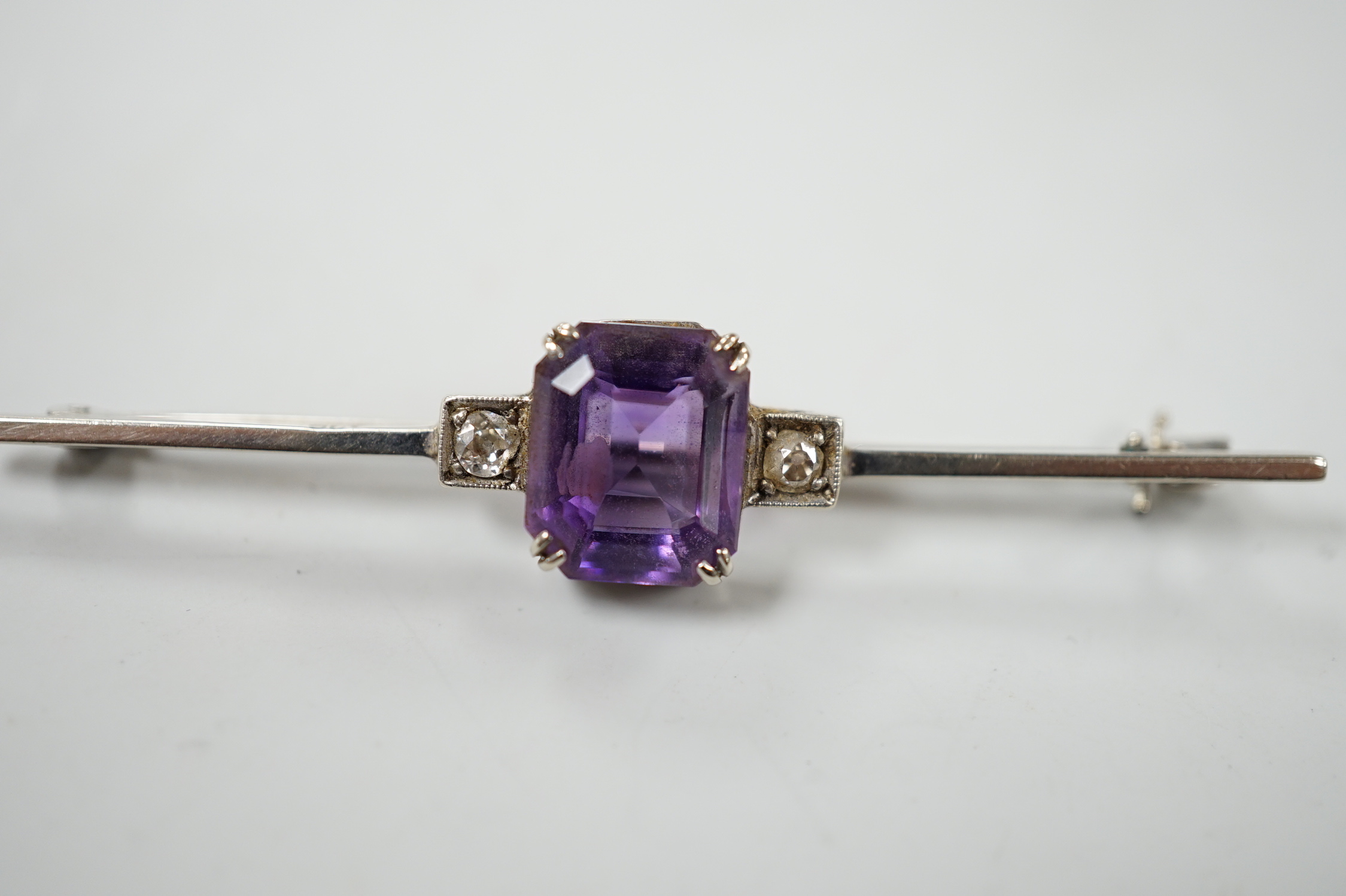 A 9ct white metal, amethyst and diamond set three stone bar brooch, 56mm, gross weight 3.7 grams, with original 1950's receipt.